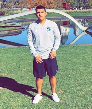 Antonio Diaz, a young man standing in front of a pond wearing a long sleeved athletic shirt and shorts